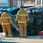 Two emergency service personnel evaluate car accident