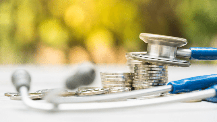 A stethoscope sits on a pile of coins.