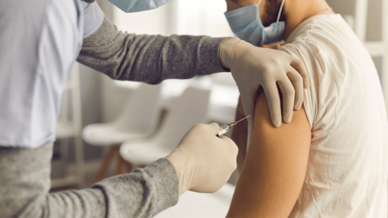 A medical professional administers a shot via syringe into a patient