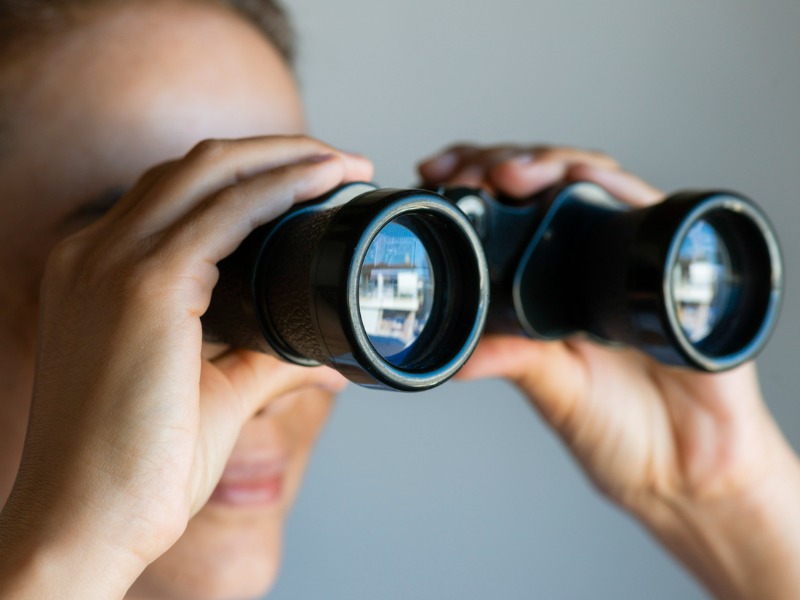 Woman looking at horizon through binoculars.