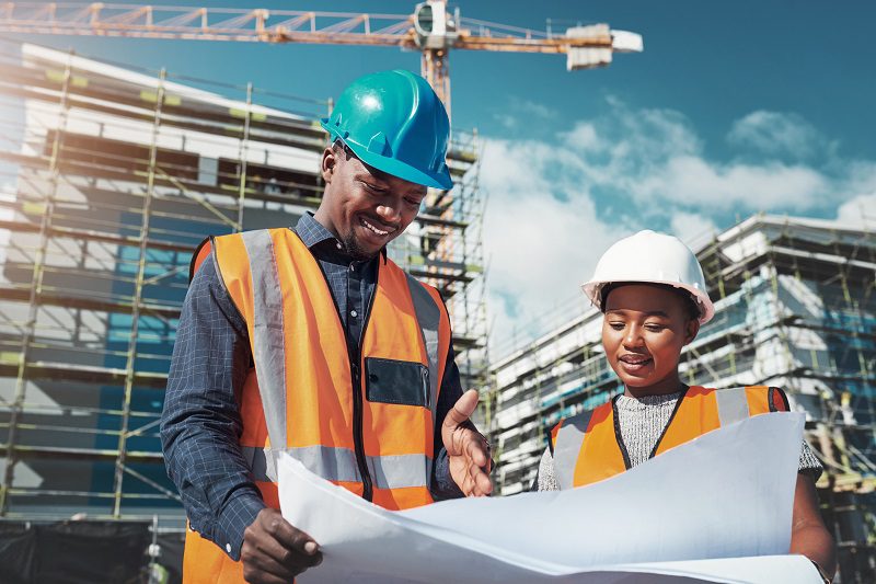 Shot of a young man and woman going over building plans at a construction site