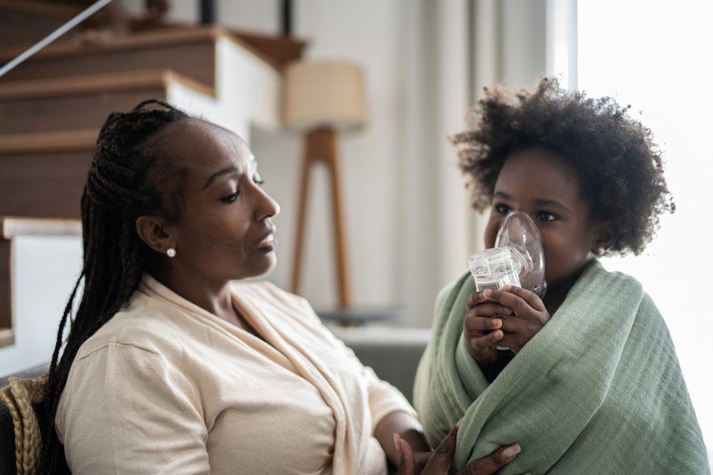 Mother helping daughter use nebulizer during inhalation therapy