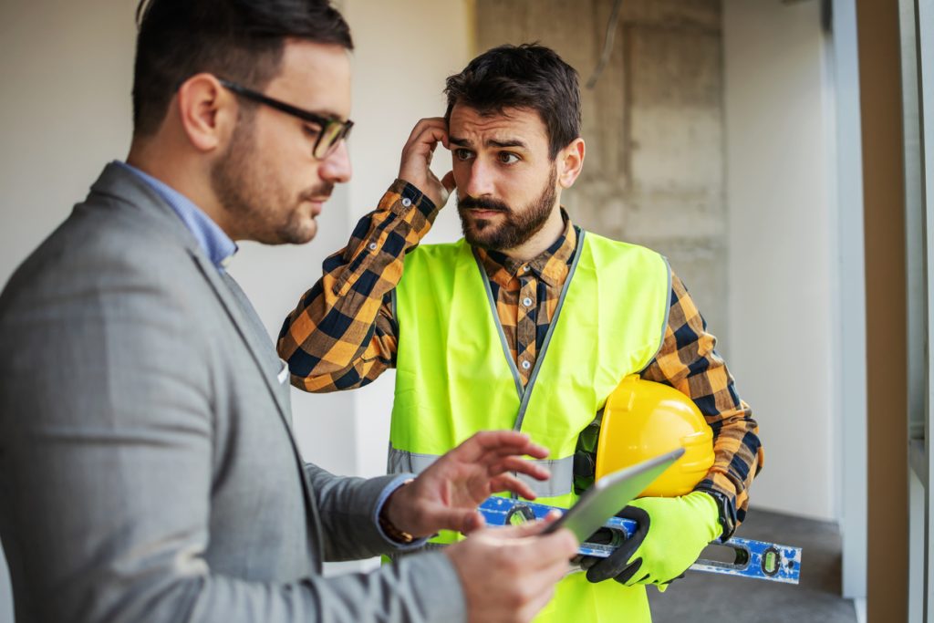 Upset construction worker looking at his supervisor and getting confused what is wrong
