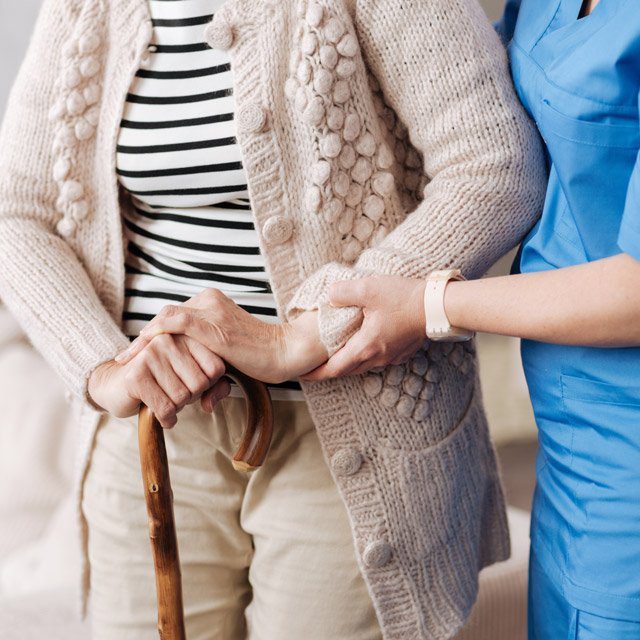 An aide helping an older woman.