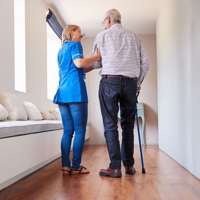 A nurse helping a man walk in a care facility. (Image: Monkey Business Images/Shutterstock)