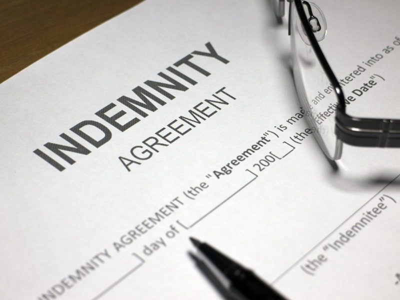 Indemnity agreement on desk with pen and eye glasses.
