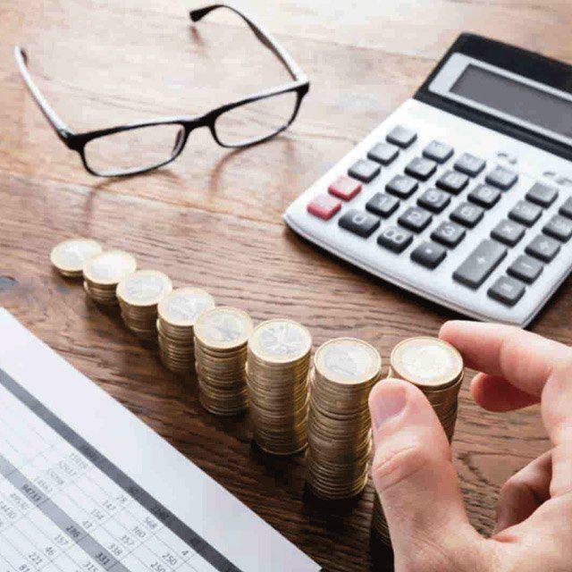 coins being sacked up next to a pair of glasses and a calculator