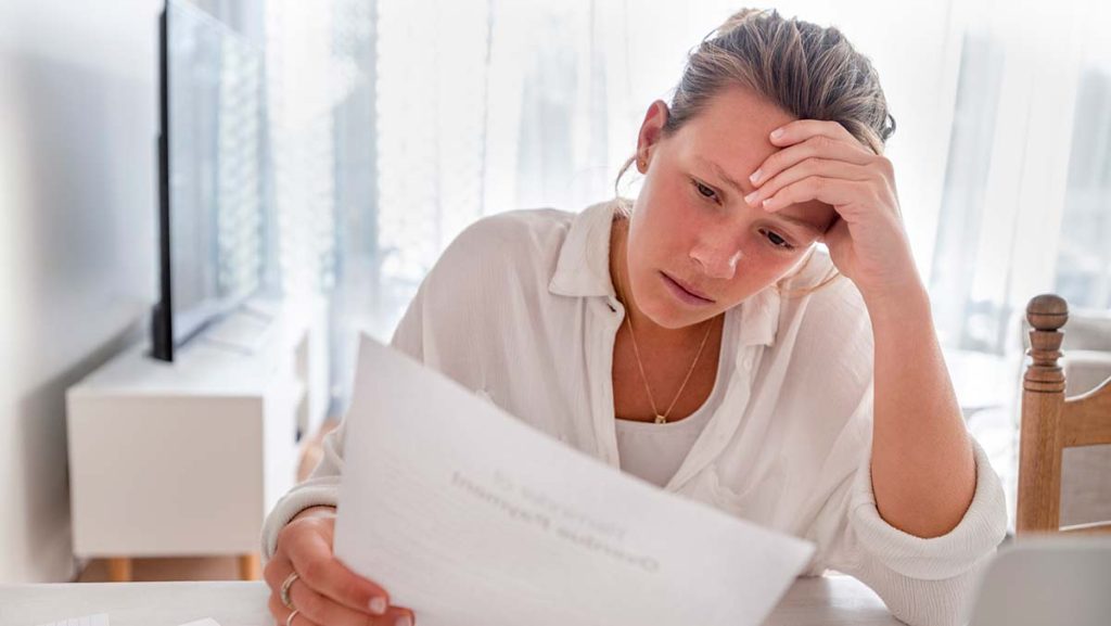 Woman concentrates while reviewing documents to understand her car insurance deductible