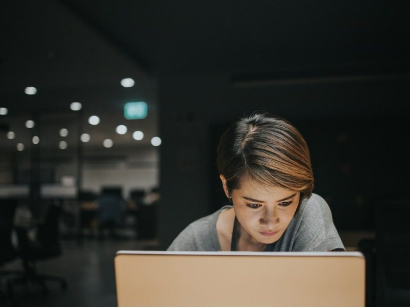 A woman leans in closely to her computer screen