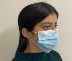 A young woman wearing a blue surgical face mask