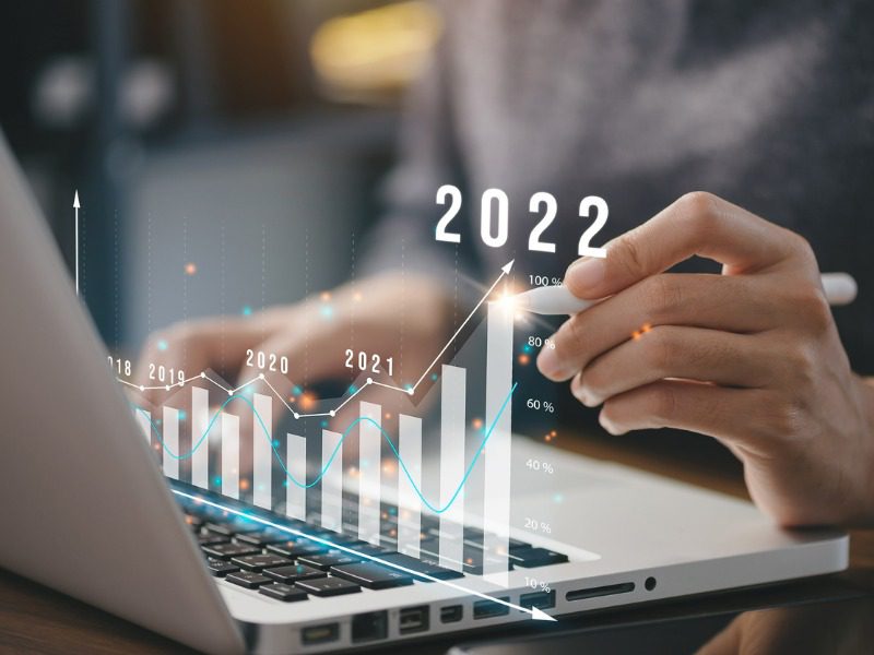 Businessperson holding a pen on an interactive bar graph, showing upwardly trending results year over year