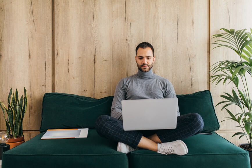 Young man working from home on his couch.