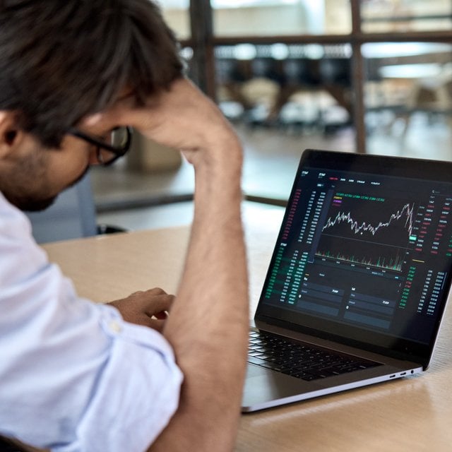 Stressed business trader analyzing stocks on a laptop