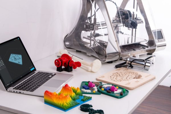3D printed objects on desk with 3D printer and laptop