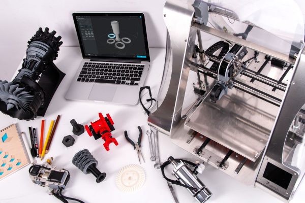 3D printer, laptop and 3D printed items on a desk