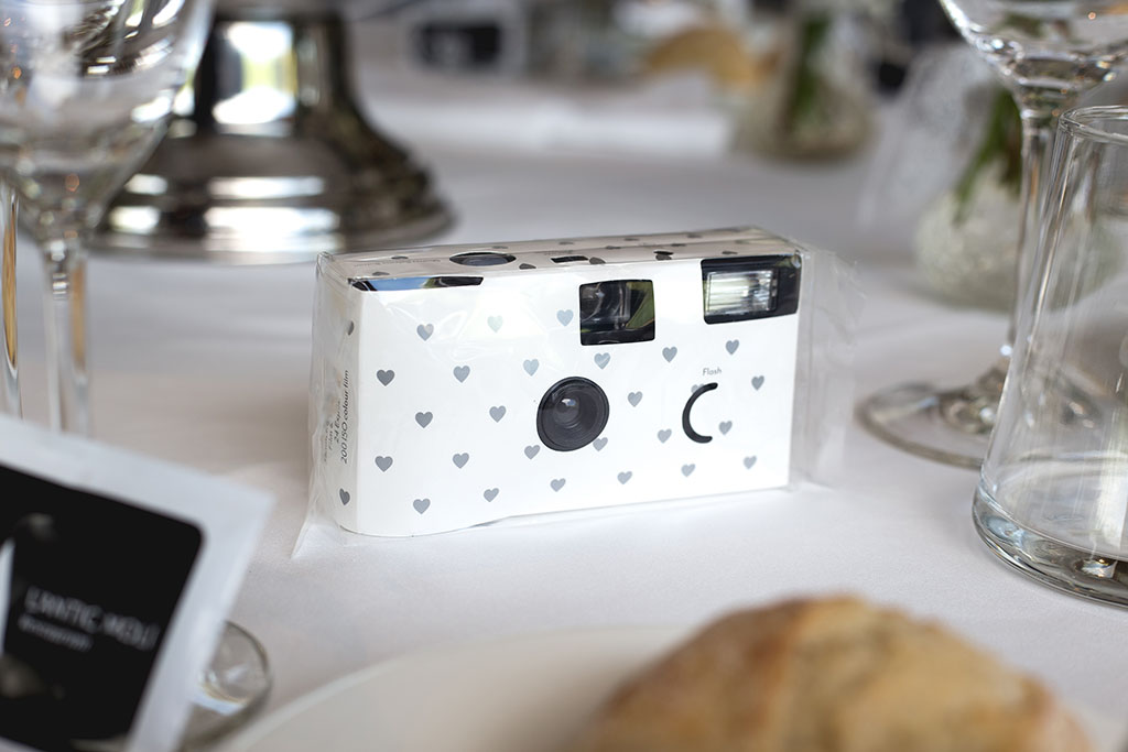 a white disposable camera sitting on a table at a wedding