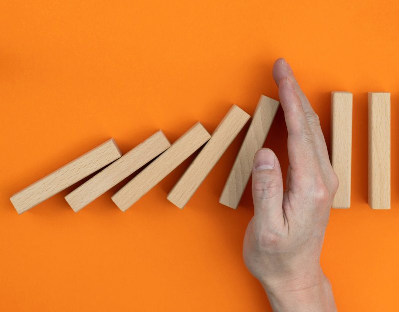 Man hand stopping the dominos falling