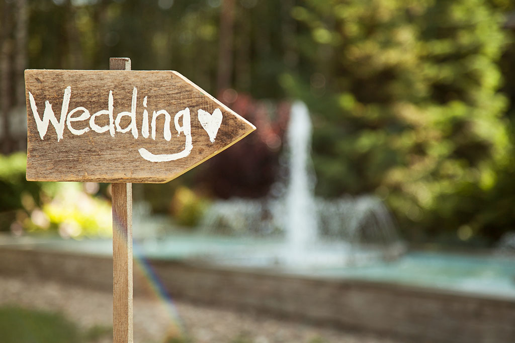 a wooden sign with wedding written on it pointing to the right to show guests where to go