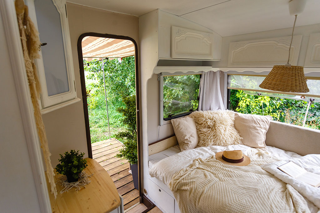 Cozy interior of a caravan with a bed, pillows and blanket
