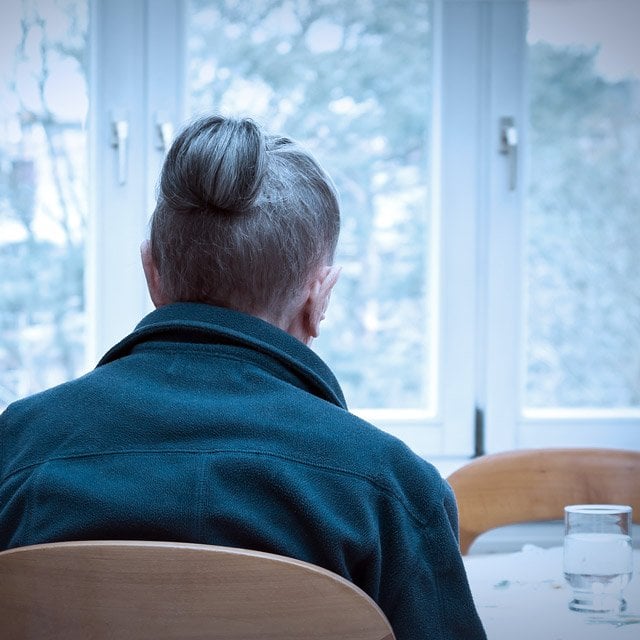 A grieving woman looks at an empty chair