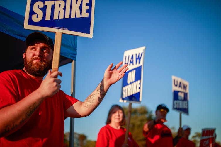 A group of autoworkers hold picket signs reading UAW on strike