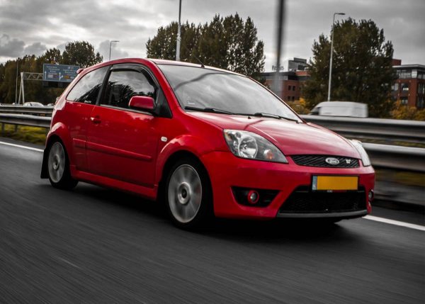Modified red Ford Fiesta driving on road