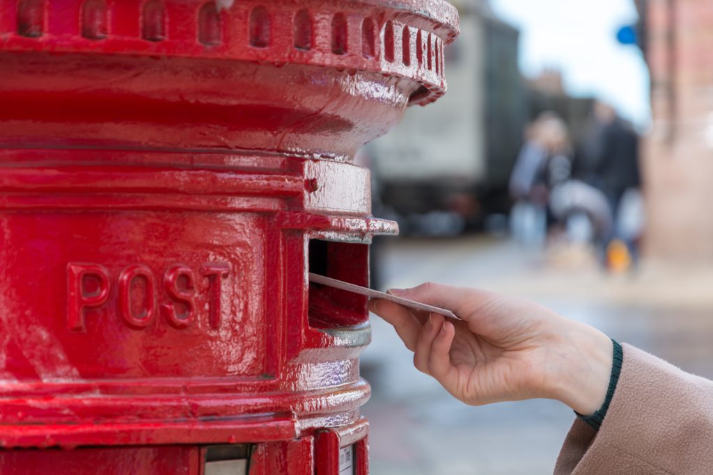 Someone posting a letter through a postbox.