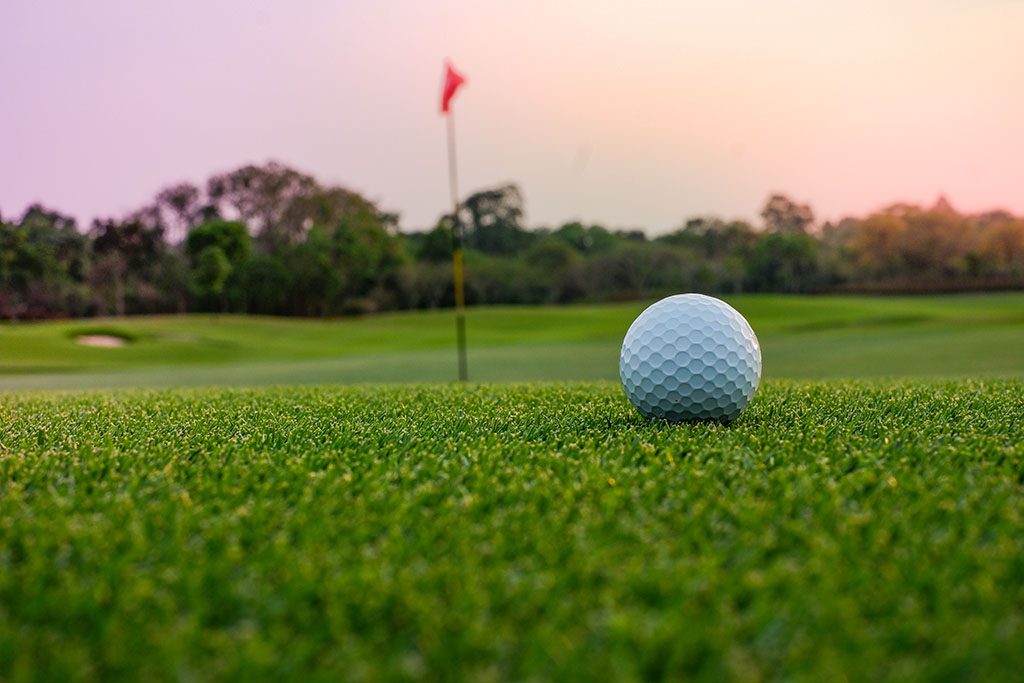 A long putt and golf ball on the  green as sunset closes in