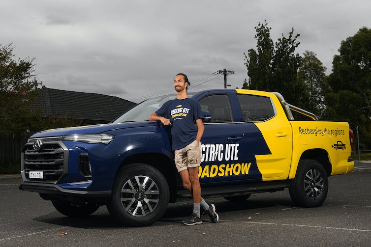 Man stands next to an electric ute with the words 'Electric Ute Roadshow' on its side