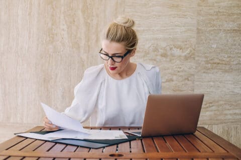 Beautiful elegant Caucasian businesswoman sitting on terrace and working with papers.