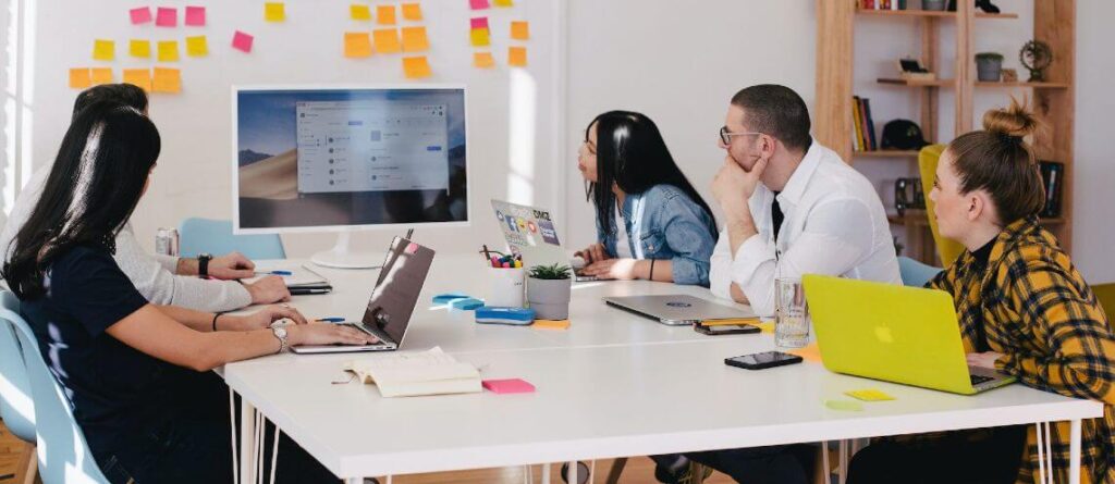 employees sitting around desk looking at computer screen