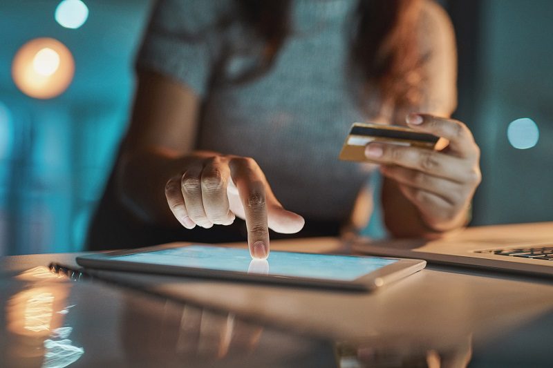 Cropped shot of an unrecognizable businesswoman using her tablet to make payments while working late in the office