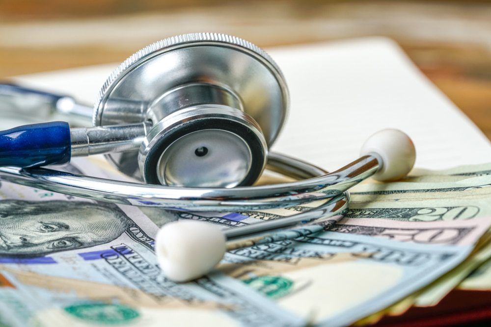 image shows a stethoscope on top of a pile of money