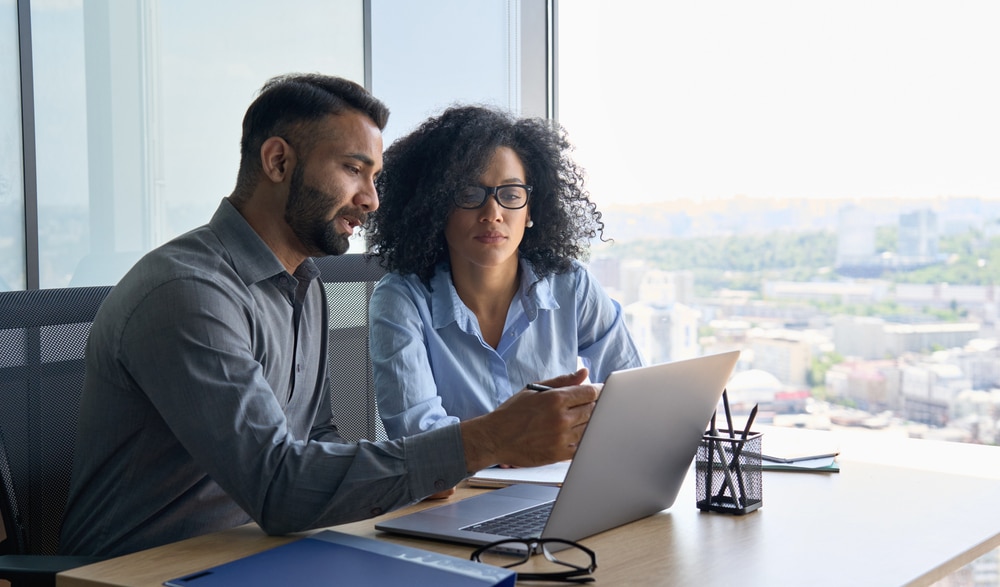 Man and woman consulting about a medical practice loan on a laptop Man and woman consulting about a medical practice loan on a laptop