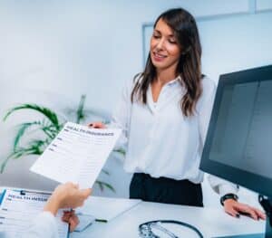 a woman handing a health insurance form to someone off camera