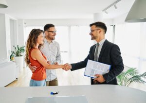 Agent with couple shaking hands closing a deal