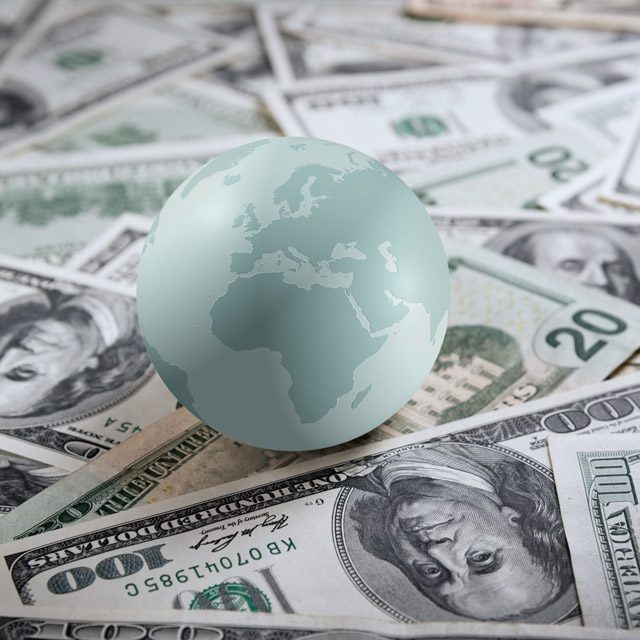 An image of a light blue plastic globe resting on $20 and $100 dollar bills from Adobe