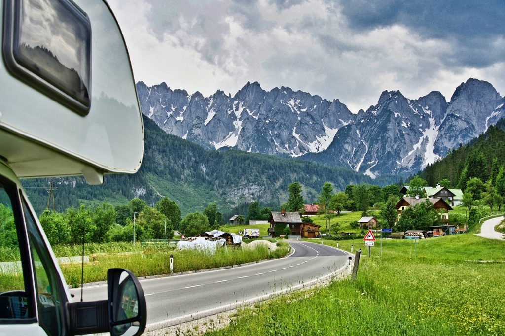 Image of a white motor home with excess insurance on a road trip through mountains