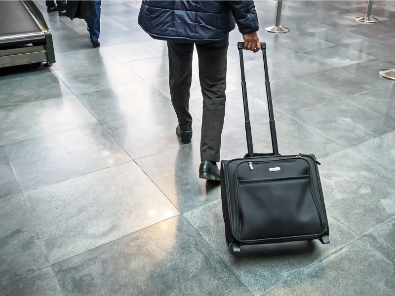 Businessman with suitcase on wheels in airport