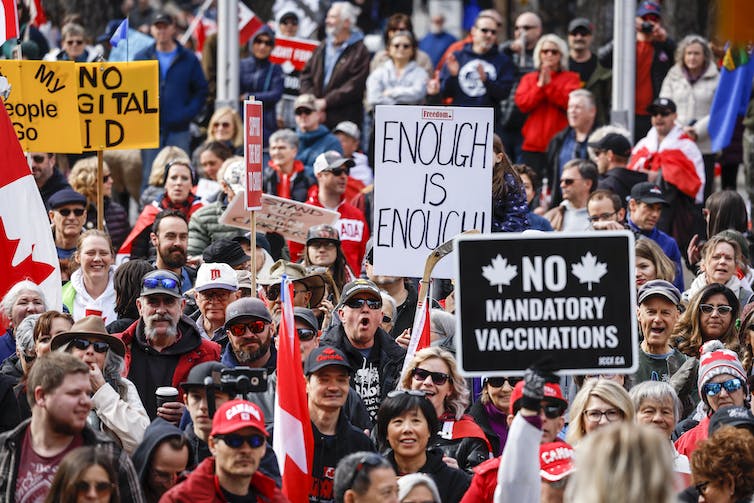 A crown of people with Canadian flags and signs reading 'Enough is enough' and 'NO mandatory vaccinations'
