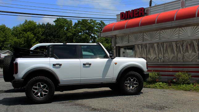 A photo of a Ford Bronco parked outside a diner. 