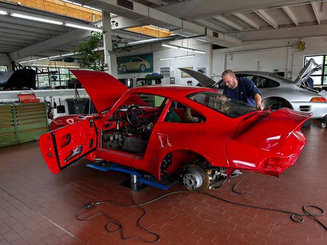 A Ruf technician works on restoring a customer's red classic turbo car