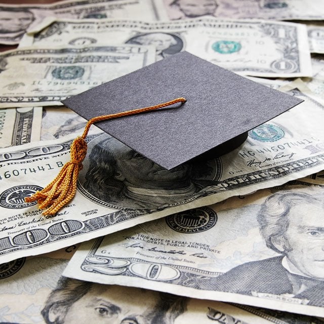 A mortarboard cap on a pile of cash