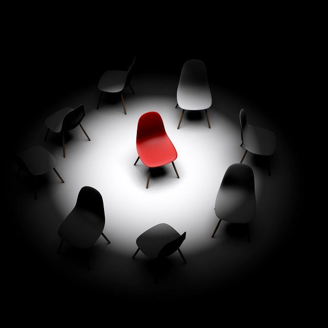Red chair in spotlight with others around it