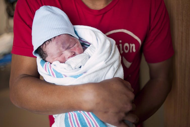A newborn baby is held by the father in a Toronto hospital.