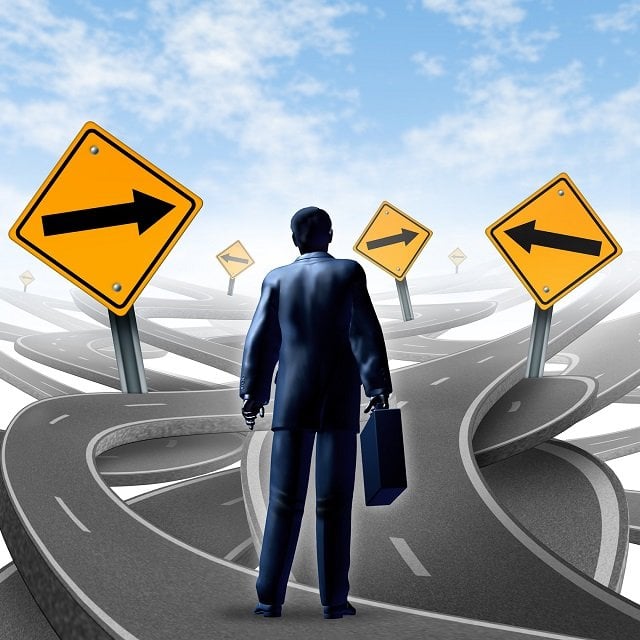 Strategic journey as a business man with a breifcase choosing the right strategic path for a new career with blank yellow traffic signs with arrows tangled roads and highways in a confused direction