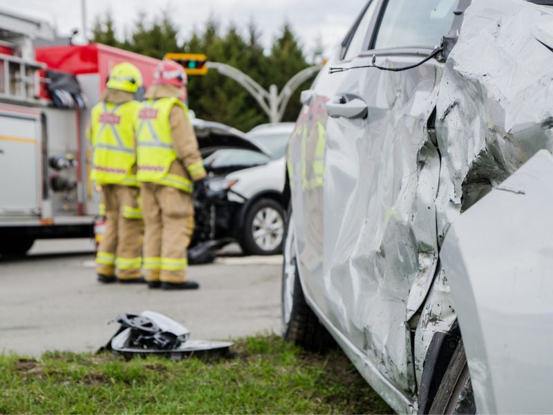 Close up on a car crash with firefighters in the background