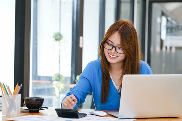 Businesswoman using a calculator to help analyze whether a life insurance settlement is a good investment