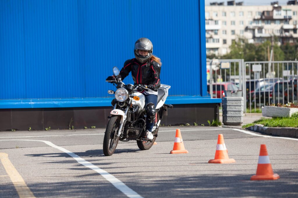 Learner motorcyclist riding slalom in between cones