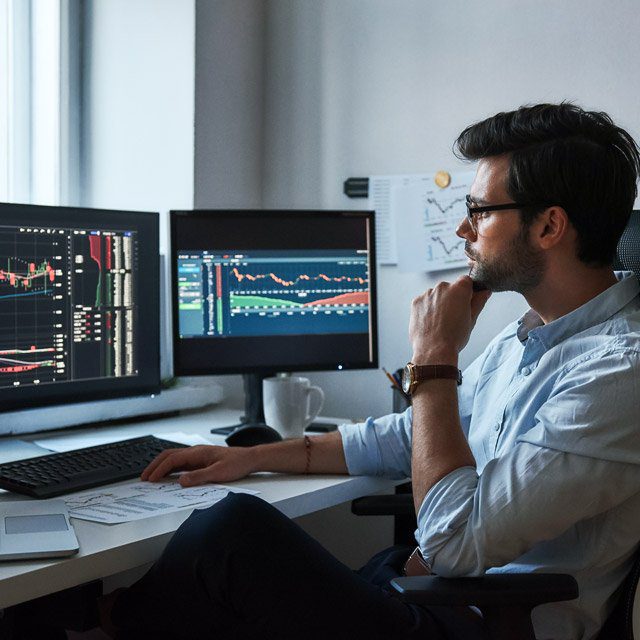 A stock trader at computer looking at charts